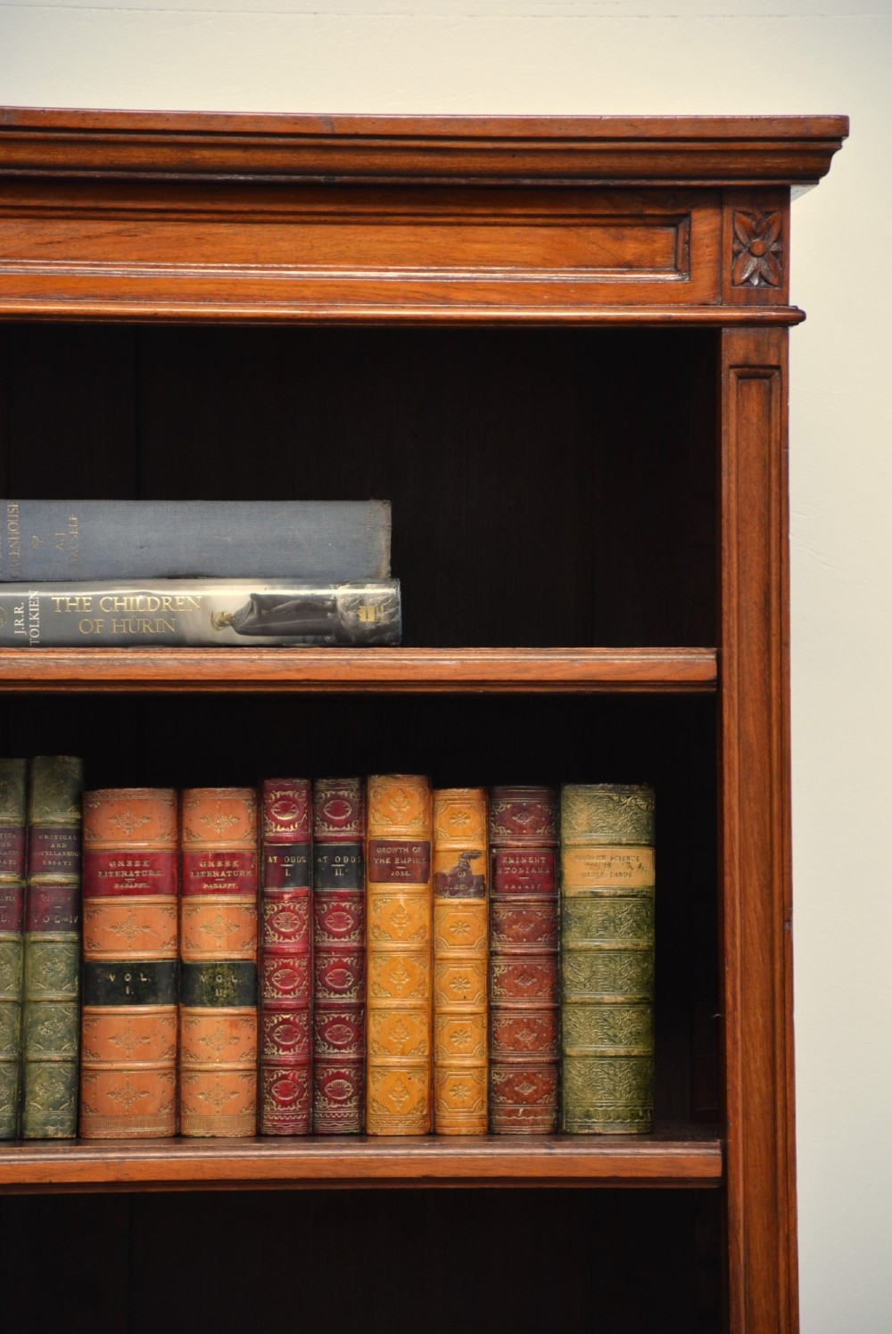 A late Victorian open walnut bookcase featuring a carved rosette frieze, moulded top cornice, adjustable shelves, and a solid plinth base. View XI
