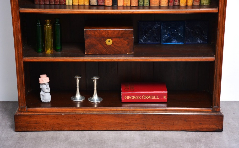 A late Victorian open walnut bookcase featuring a carved rosette frieze, moulded top cornice, adjustable shelves, and a solid plinth base. View XII
