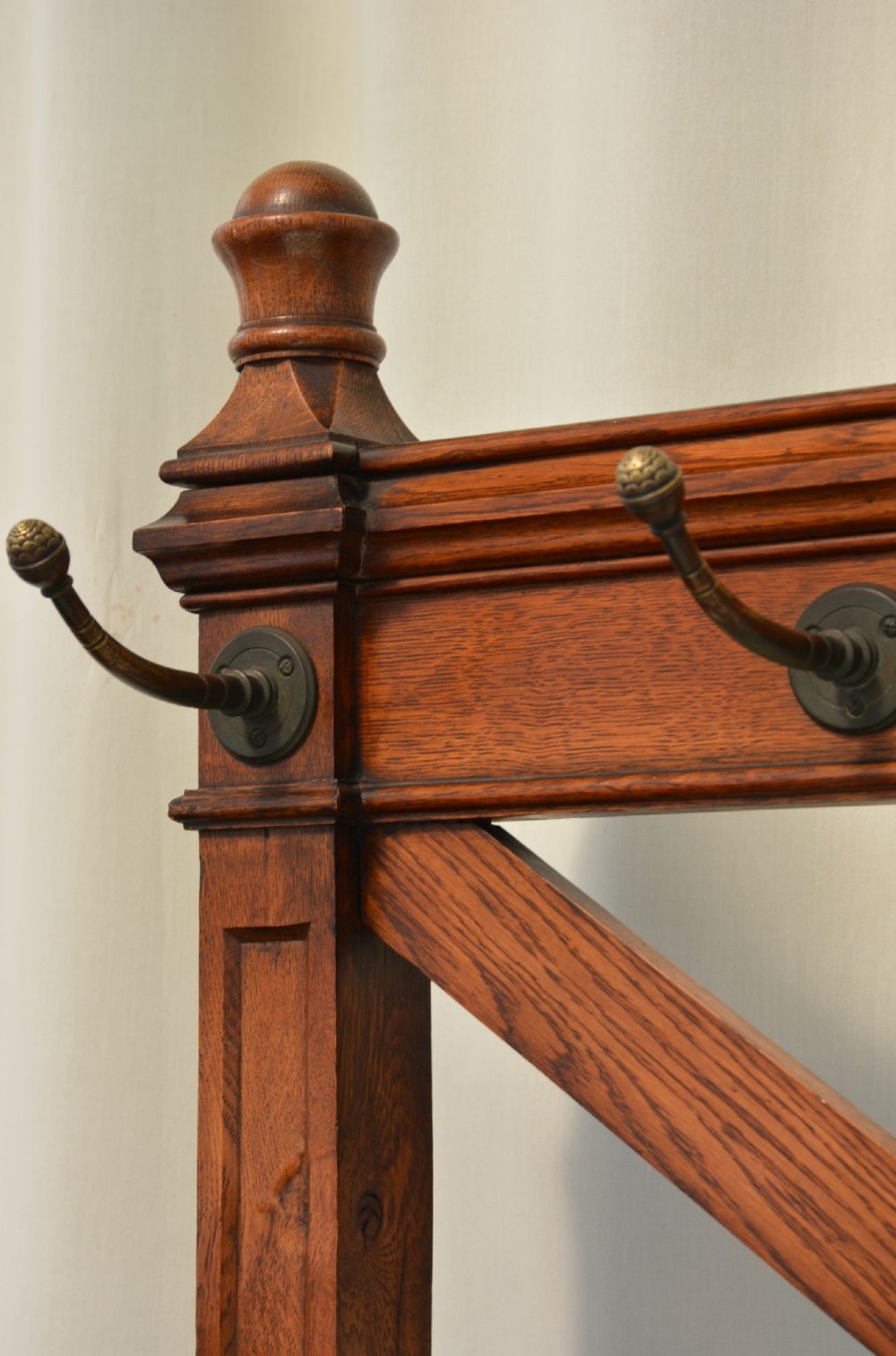 A Gothic Revival solid oak freestanding coat stand featuring upper hooks, carved diamond lattice fretwork, turned finials, and a shaped trestle base. View VII