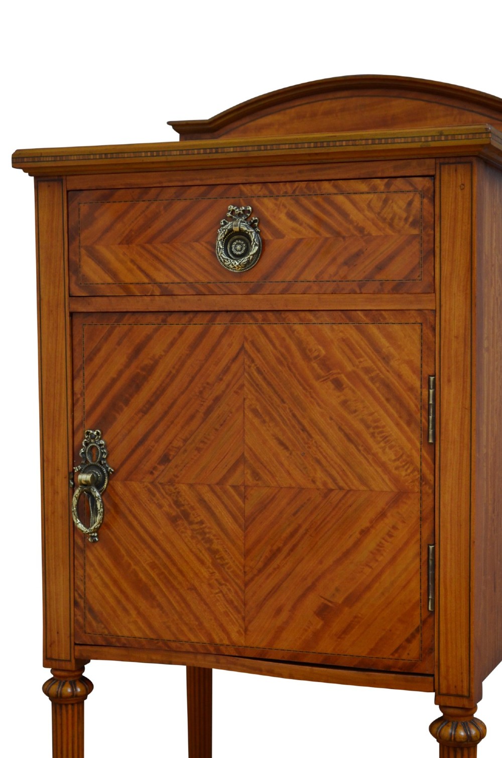 An antique satinwood bedside cupboard featuring a shaped gallery back, top drawer, chevron parquetry cupboard door, and slender fluted legs. View VI