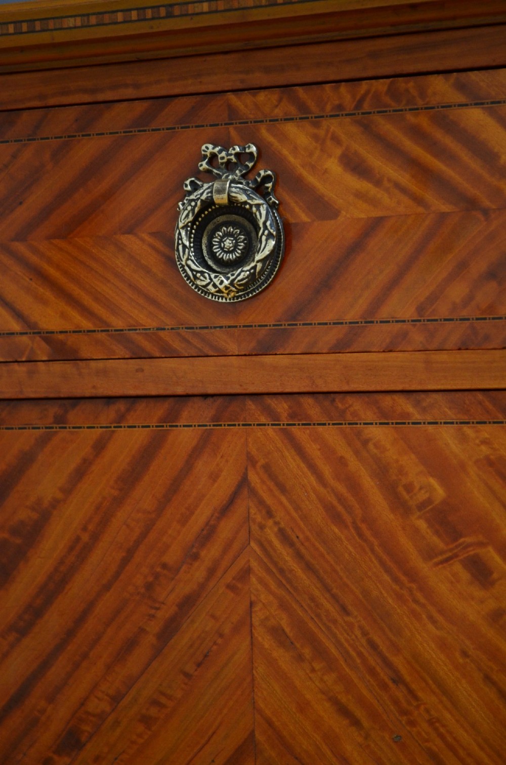 An antique satinwood bedside cupboard featuring a shaped gallery back, top drawer, chevron parquetry cupboard door, and slender fluted legs. View VIII