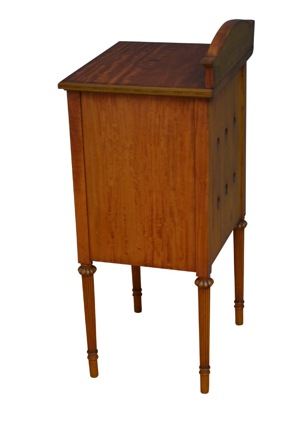 An antique satinwood bedside cupboard featuring a shaped gallery back, top drawer, chevron parquetry cupboard door, and slender fluted legs. View XI