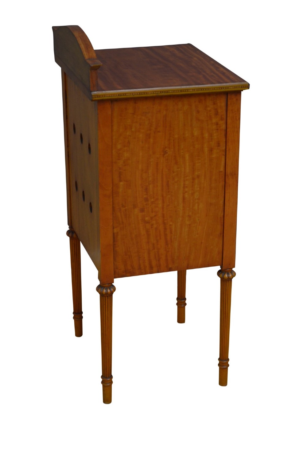 An antique satinwood bedside cupboard featuring a shaped gallery back, top drawer, chevron parquetry cupboard door, and slender fluted legs. View XII