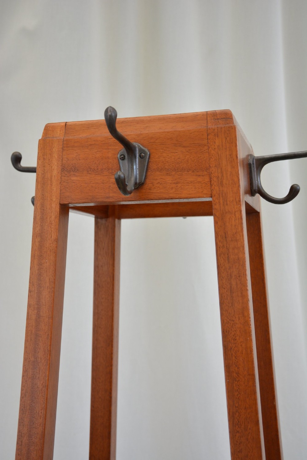 A tall tapered solid mahogany hall coat stand featuring top metal hooks, an umbrella divider section, and a dark metal drip tray base. View VII