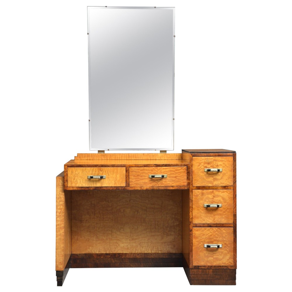 An Art Deco asymmetrical dressing table crafted in burr maple veneer with an offset pedestal of drawers and a large frameless mirror.