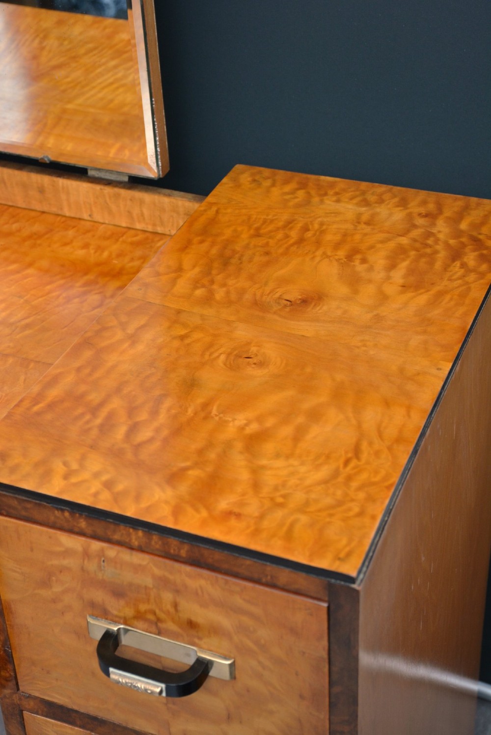 An Art Deco asymmetrical dressing table crafted in burr maple veneer with an offset pedestal of drawers and a large frameless mirror. View VI