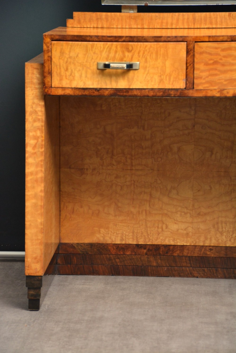 An Art Deco asymmetrical dressing table crafted in burr maple veneer with an offset pedestal of drawers and a large frameless mirror. View XII