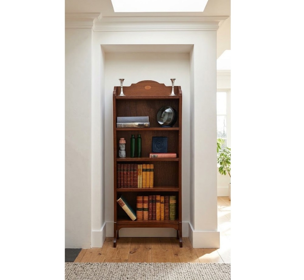 A slim Edwardian open mahogany bookcase featuring four fixed shelves, a shaped top gallery with a central oval inlay, and bracket feet. View II