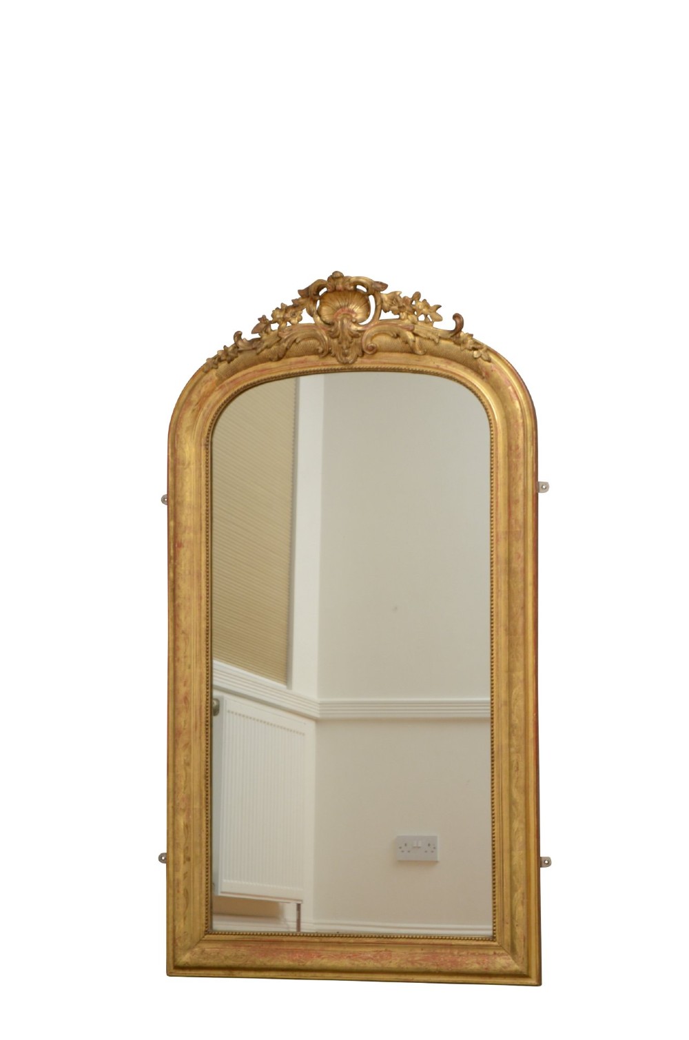 A tall arched French Napoleon III wall mirror featuring a gilded frame with a carved shell and foliage crest.