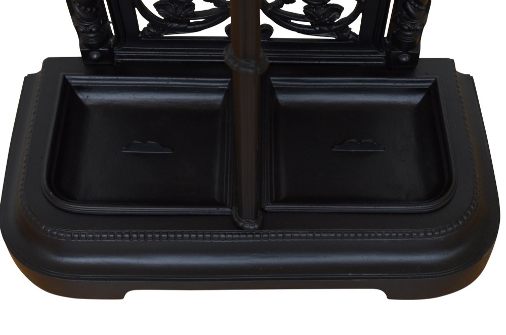 A black cast iron umbrella stand featuring an ornate foliate backplate, top support rail, and a twin-section drip tray at the base. View VIII