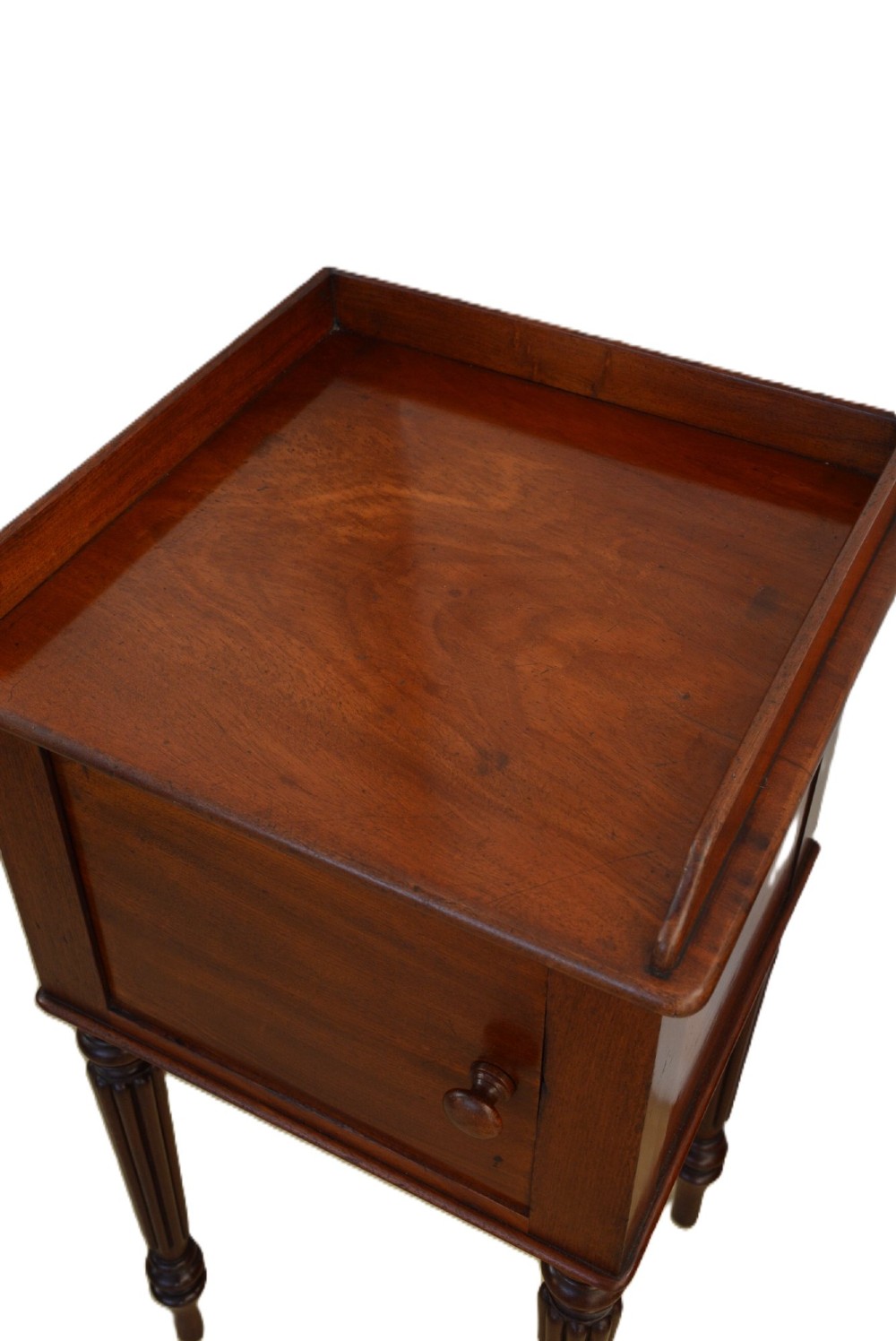 A William IV mahogany nightstand featuring a gallery top, a single door cupboard with a turned wooden knob, and four slender reeded tapering legs. View IX