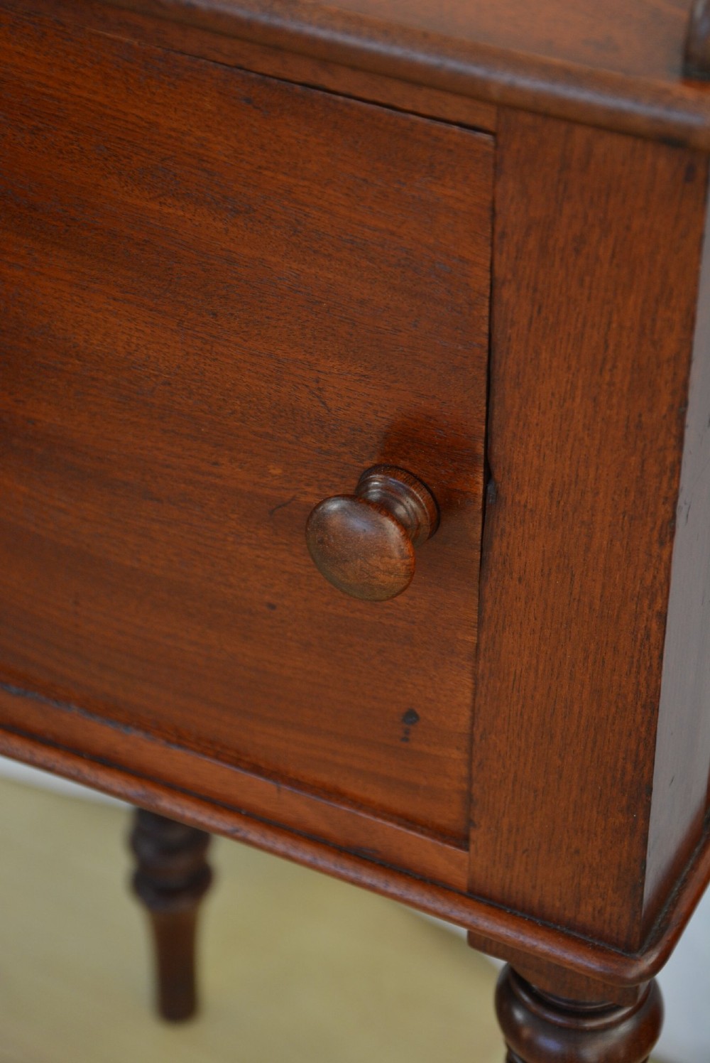 A William IV mahogany nightstand featuring a gallery top, a single door cupboard with a turned wooden knob, and four slender reeded tapering legs. View X