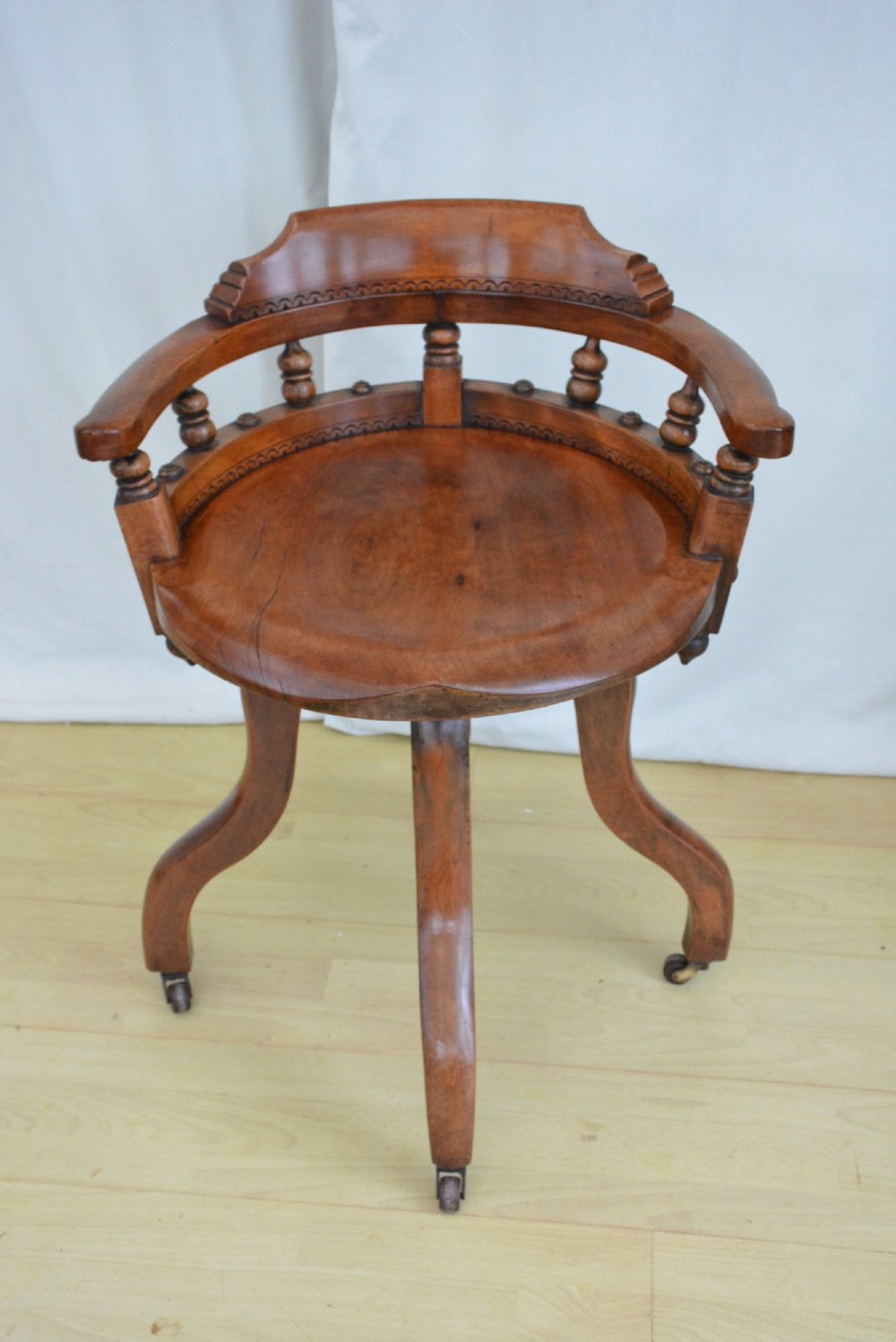 A 19th-century Victorian walnut revolving desk chair featuring a curved backrest with turned spindles, a contoured solid seat, and splayed legs on castors. View VIII