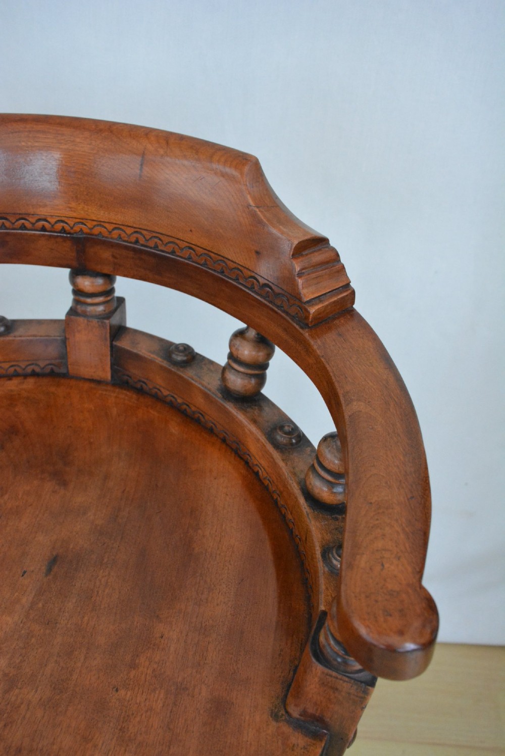 A 19th-century Victorian walnut revolving desk chair featuring a curved backrest with turned spindles, a contoured solid seat, and splayed legs on castors. View XII