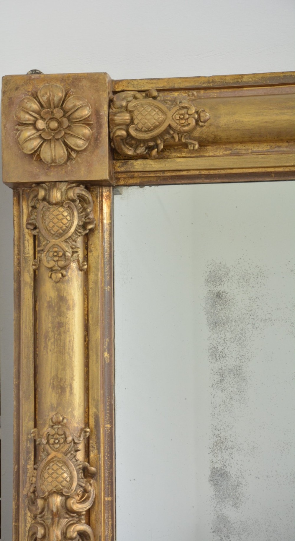 A large 19th-century rectangular giltwood overmantel mirror featuring carved corner rosettes and floral mouldings. View III