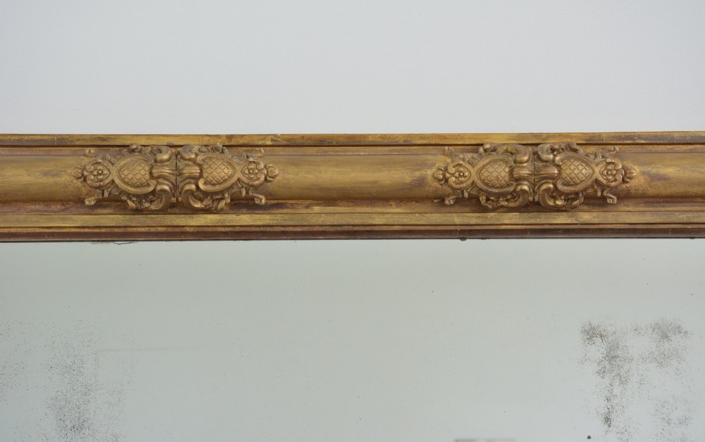 A large 19th-century rectangular giltwood overmantel mirror featuring carved corner rosettes and floral mouldings. View IV