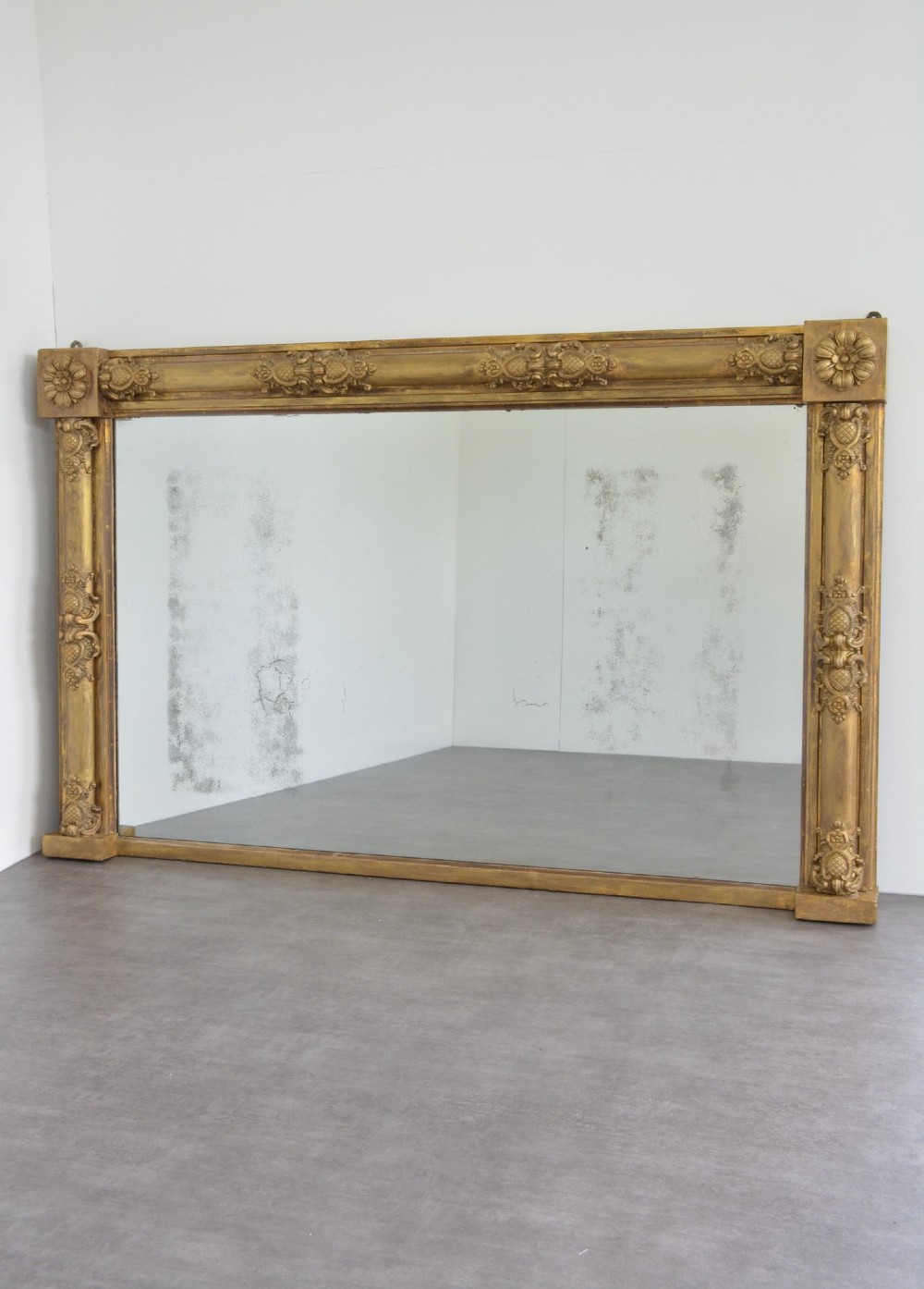 A large 19th-century rectangular giltwood overmantel mirror featuring carved corner rosettes and floral mouldings. View V