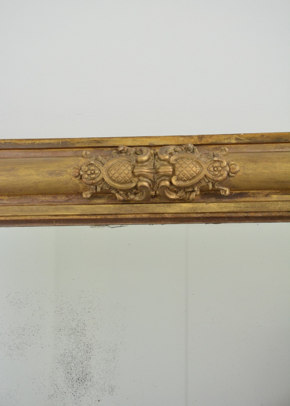 A large 19th-century rectangular giltwood overmantel mirror featuring carved corner rosettes and floral mouldings. View XII