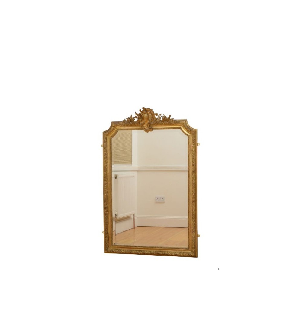 A tall French giltwood wall mirror featuring a carved foliate crest and a moulded gold frame. View II