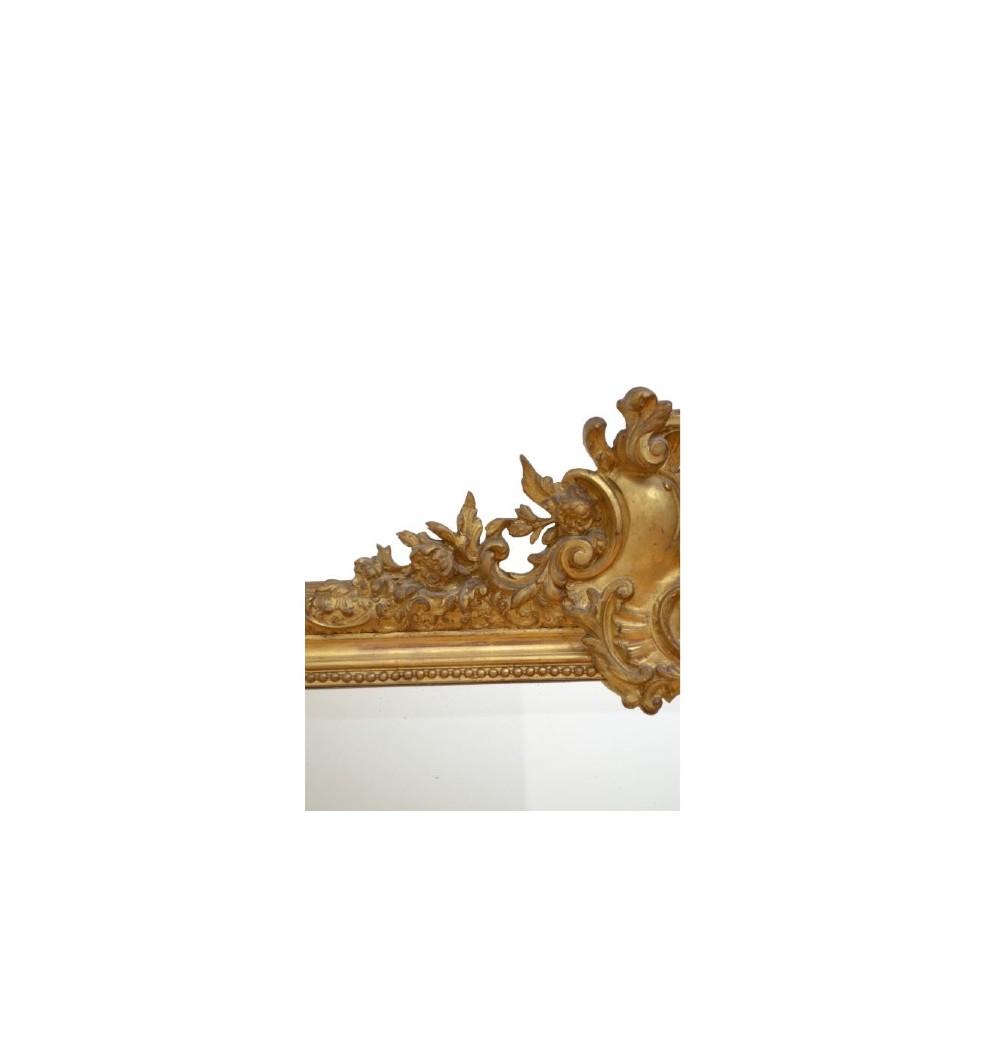 A tall French giltwood wall mirror featuring a carved foliate crest and a moulded gold frame. View IV