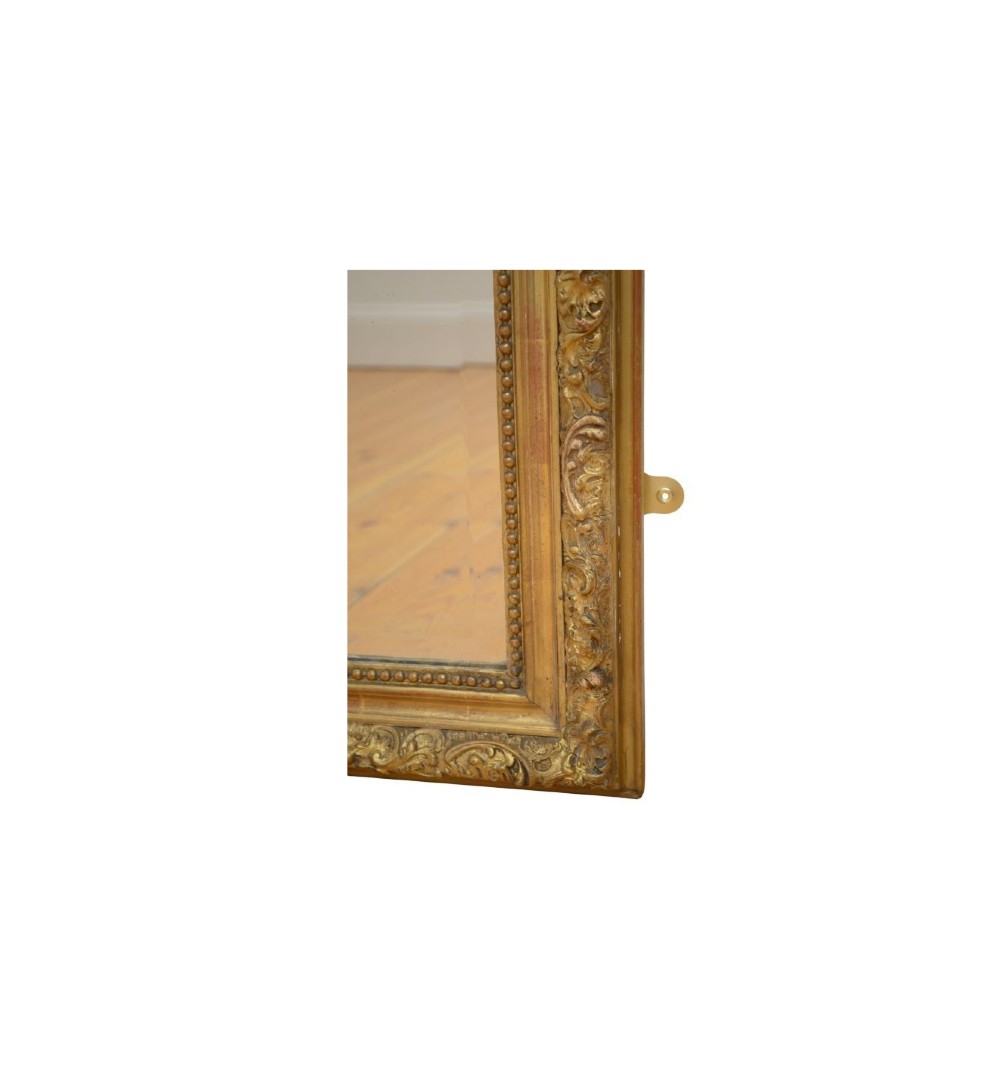 A tall French giltwood wall mirror featuring a carved foliate crest and a moulded gold frame. View V