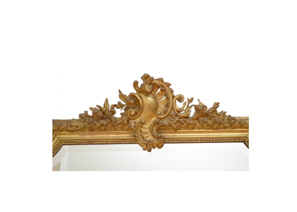 A tall French giltwood wall mirror featuring a carved foliate crest and a moulded gold frame. View X