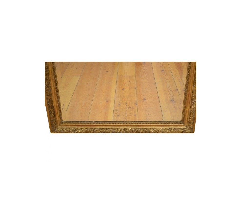 A tall French giltwood wall mirror featuring a carved foliate crest and a moulded gold frame. View XI
