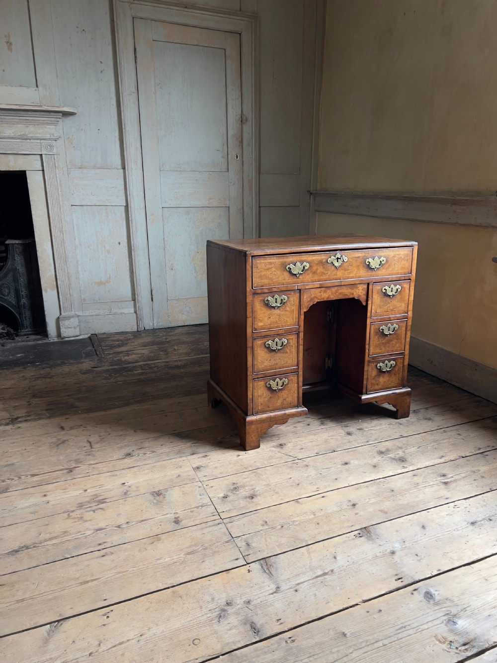 An 18th-century George II burr walnut kneehole desk featuring multiple drawers with brass handles, a central recessed cupboard, and bracket feet. View II
