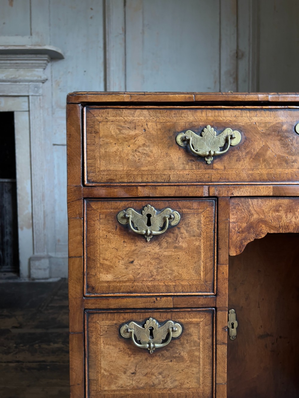 An 18th-century George II burr walnut kneehole desk featuring multiple drawers with brass handles, a central recessed cupboard, and bracket feet. View VI