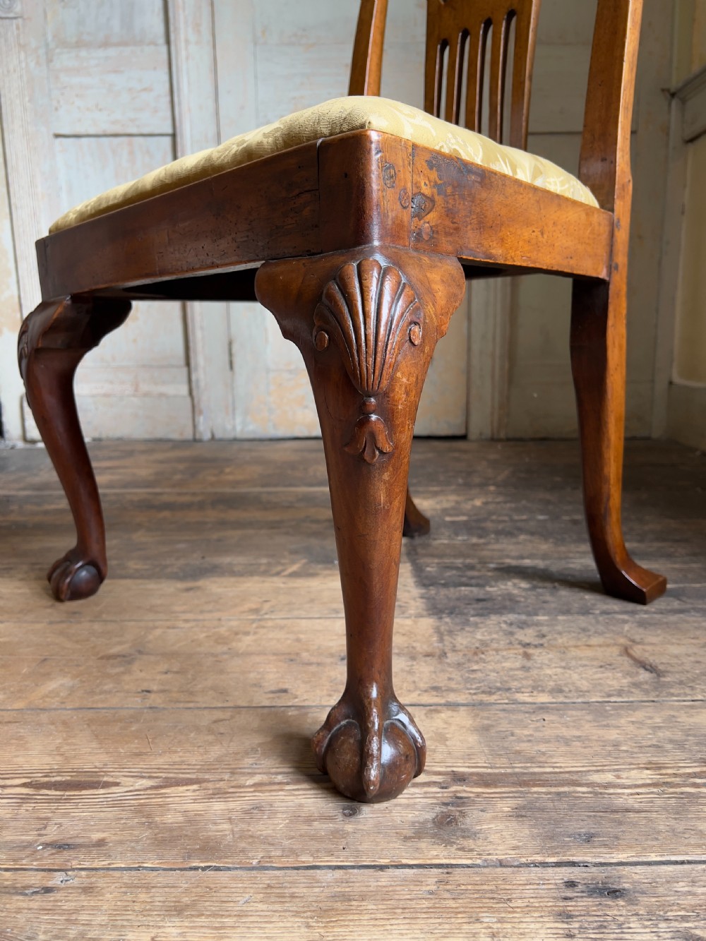 A George II period walnut side chair featuring a carved splat back, yellow damask seat cushion, and cabriole legs with claw-and-ball feet. View V