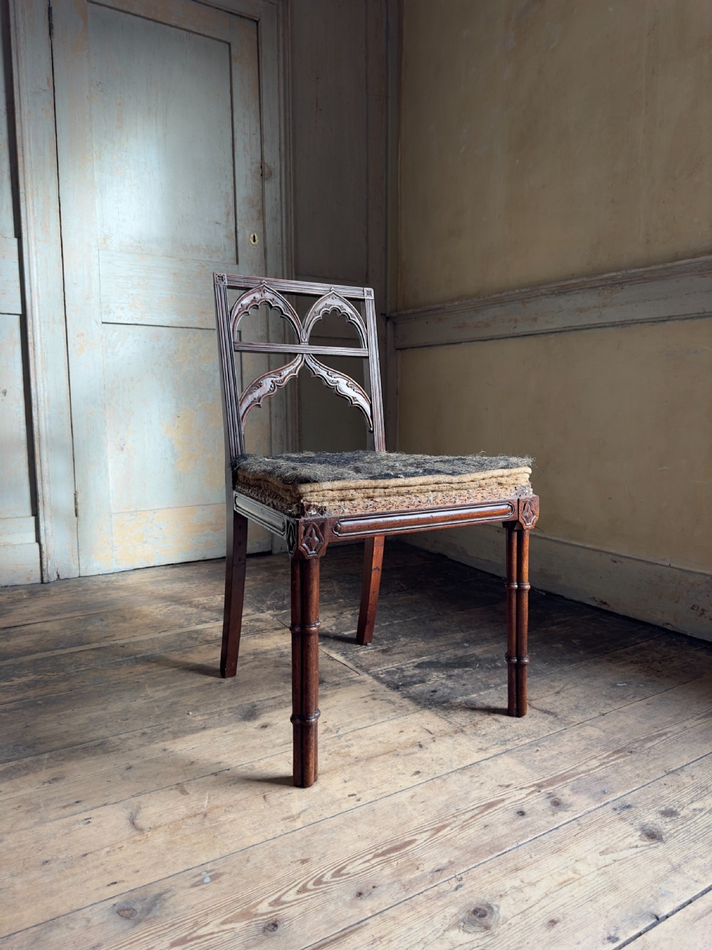 An antique Georgian mahogany side chair featuring carved Gothic tracery in the backrest and turned legs.