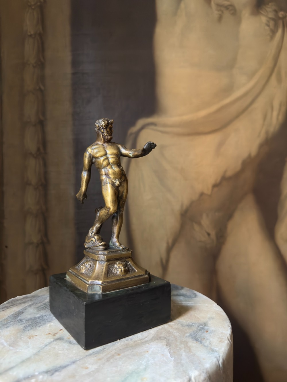 An 18th-century bronze statuette depicting the classical figure Neptune standing in contrapposto on a detailed pedestal and dark marble base.