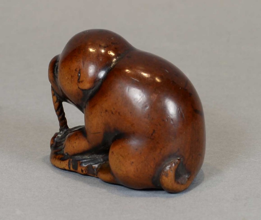 A DELIGHTFUL EDO PERIOD BOXWOOD NETSUKE OF AN AKITA PUPPY HOLDING AN ABALONE-SHELL TOY View VII