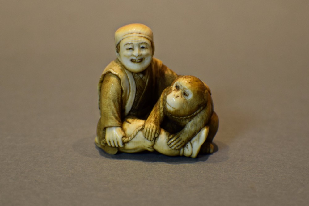 A CHARMING JAPANESE IVORY OKIMONO OF A SEATED MONKEY & SARUMAWASHI- SIGNED