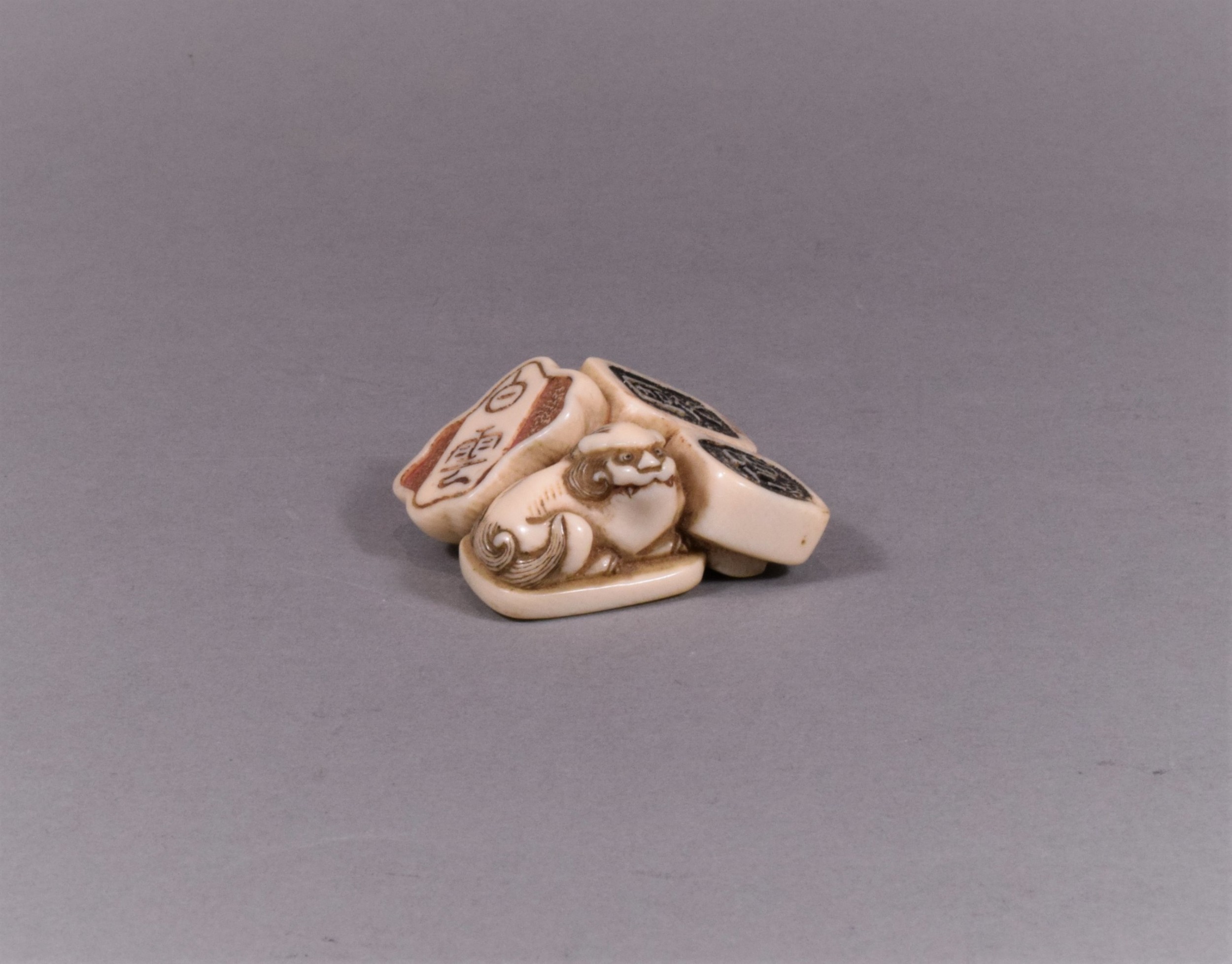 A JAPANESE EDO PERIOD IVORY NETSUKE OF SEALS - SHI SHI DOG View II