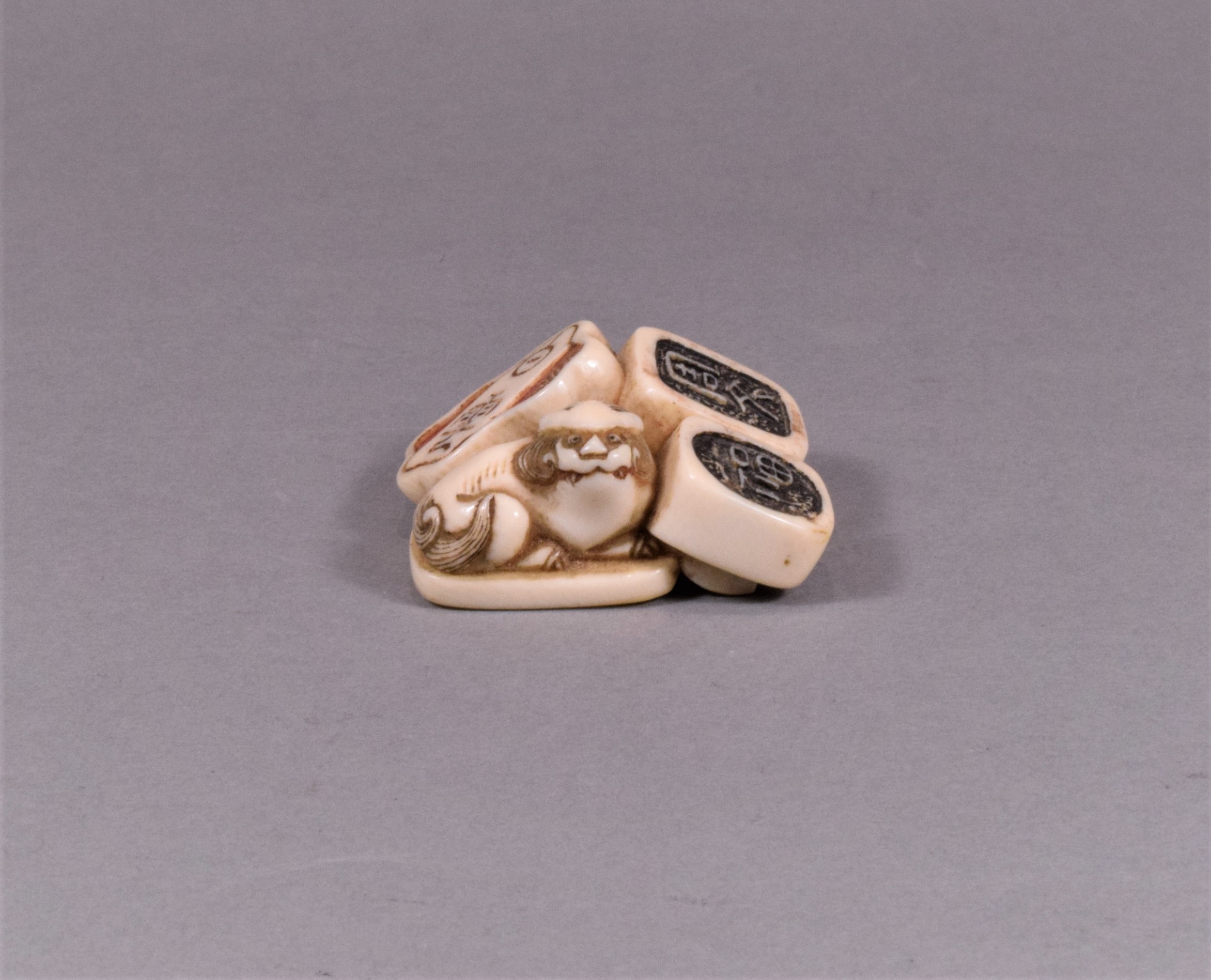 A JAPANESE EDO PERIOD IVORY NETSUKE OF SEALS - SHI SHI DOG View III
