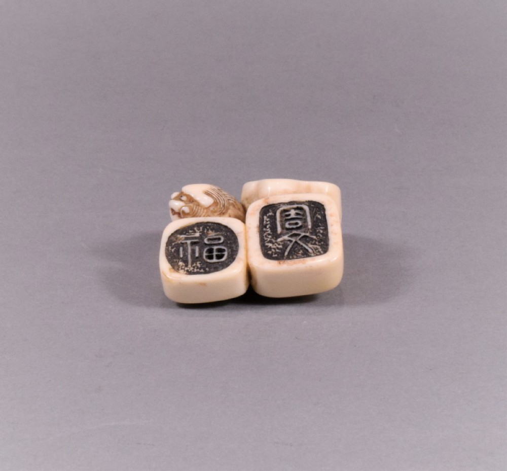 A JAPANESE EDO PERIOD IVORY NETSUKE OF SEALS - SHI SHI DOG View IV