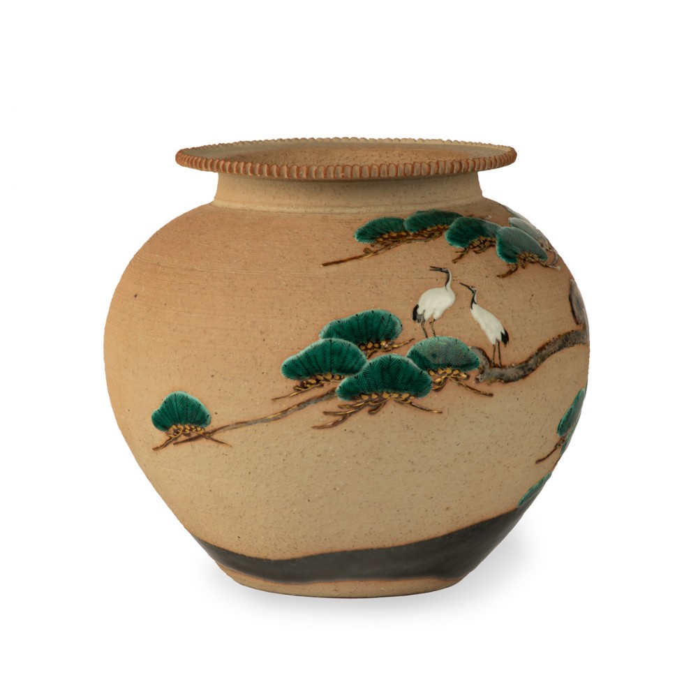 A rounded Japanese stoneware jardiniere crafted in buff clay with relief carvings of white cranes perched on green pine branches. View III