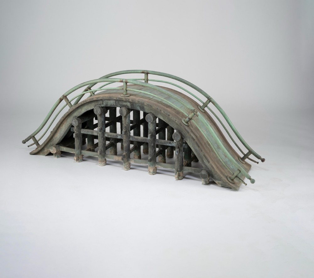 An arched Japanese cast bronze drum bridge model with a verdigris green patina and detailed underlying timber support structure.