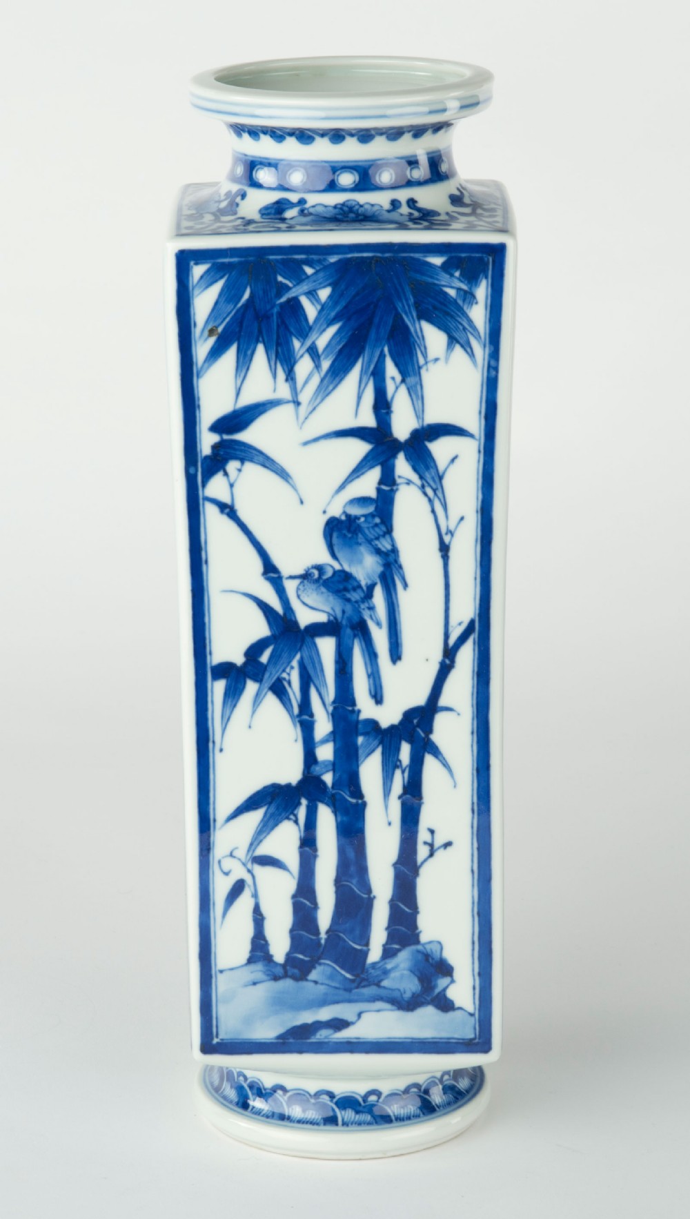 A tall quadrangular Japanese porcelain vase decorated with underglaze cobalt blue landscape scenes and geometric panels on a white ground. View VI
