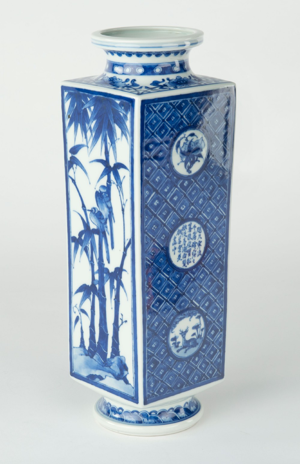 A tall quadrangular Japanese porcelain vase decorated with underglaze cobalt blue landscape scenes and geometric panels on a white ground. View VII