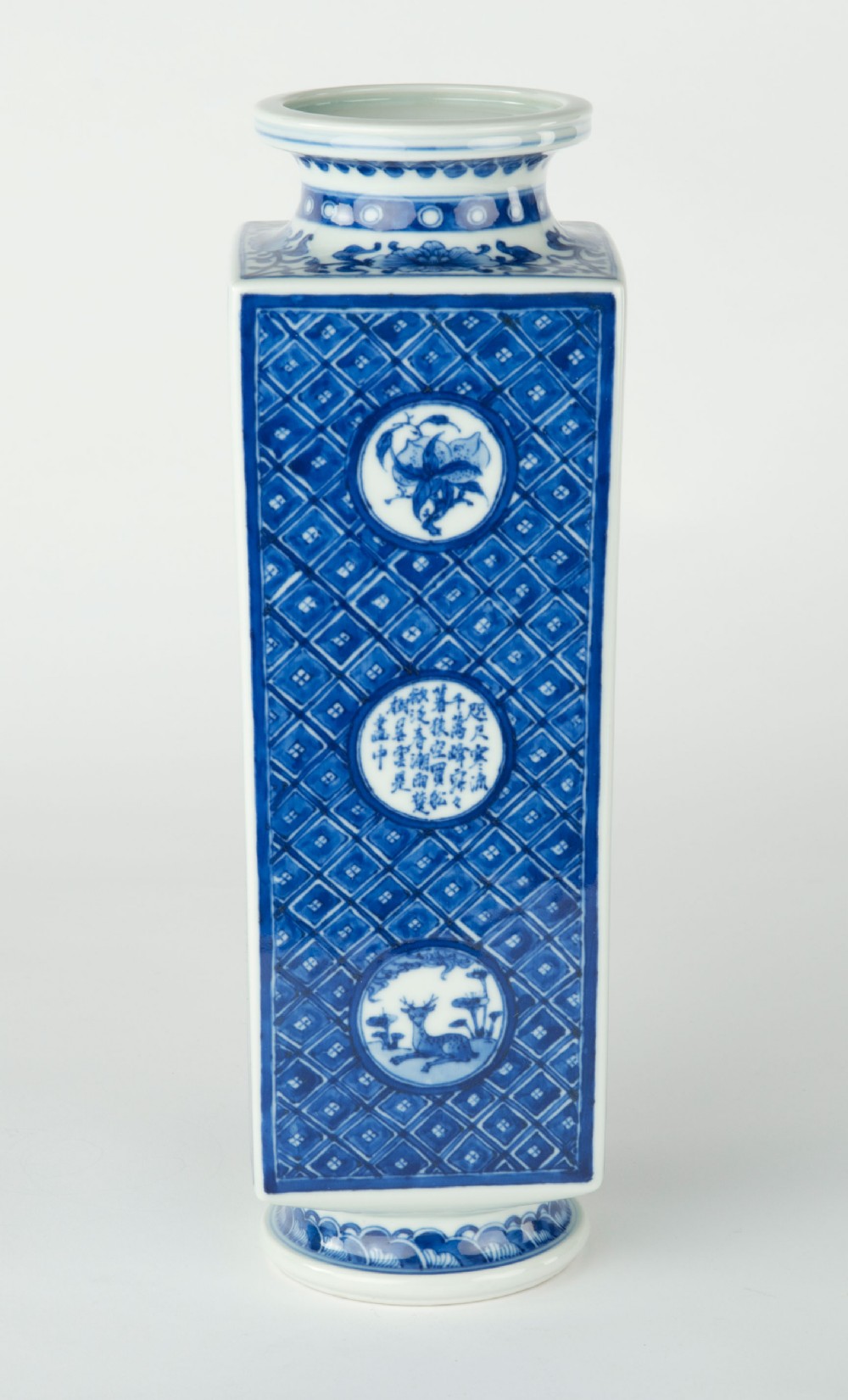 A tall quadrangular Japanese porcelain vase decorated with underglaze cobalt blue landscape scenes and geometric panels on a white ground. View VIII