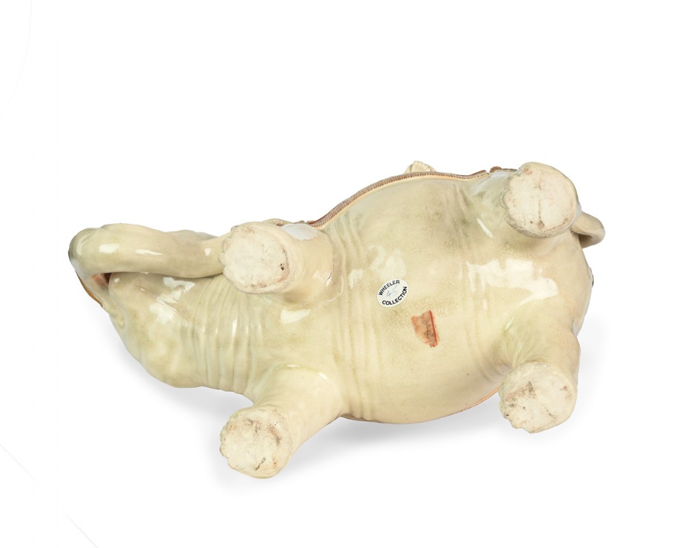 A Japanese Satsuma ceramic okimono depicting a figure adorned in elaborate polychrome robes seated atop a cream-coloured elephant with gilded accents. View V