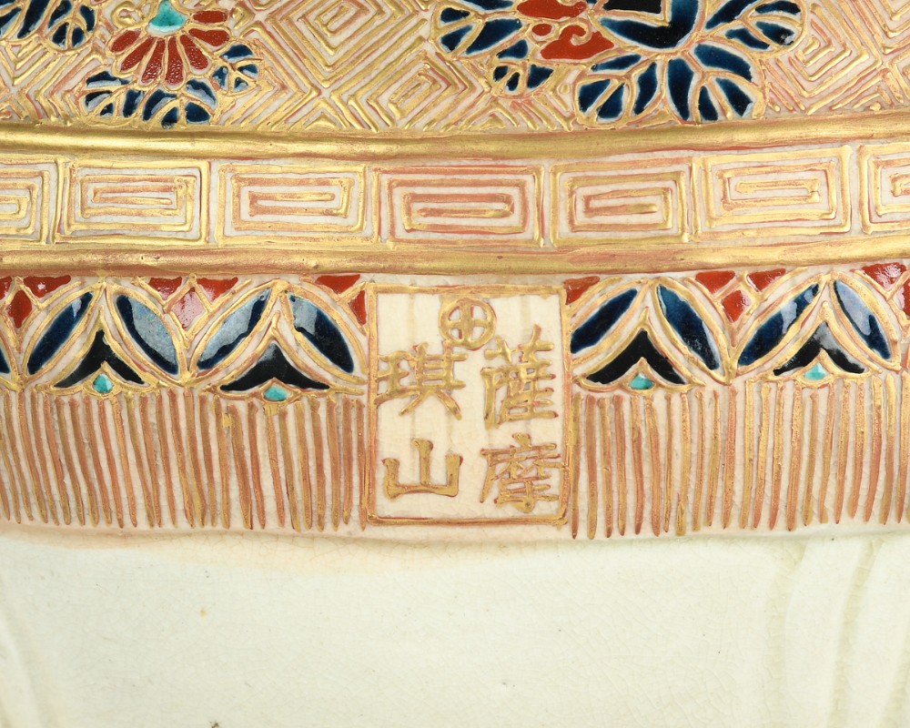A Japanese Satsuma ceramic okimono depicting a figure adorned in elaborate polychrome robes seated atop a cream-coloured elephant with gilded accents. View VII