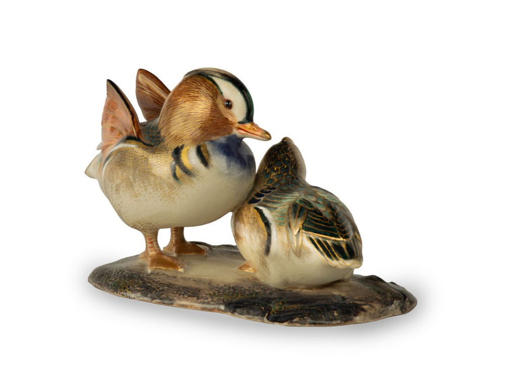 A Japanese porcelain sculpture depicting a pair of Mandarin ducks with detailed polychrome enamel feathers and gilt accents set on a dark textured base. View IV