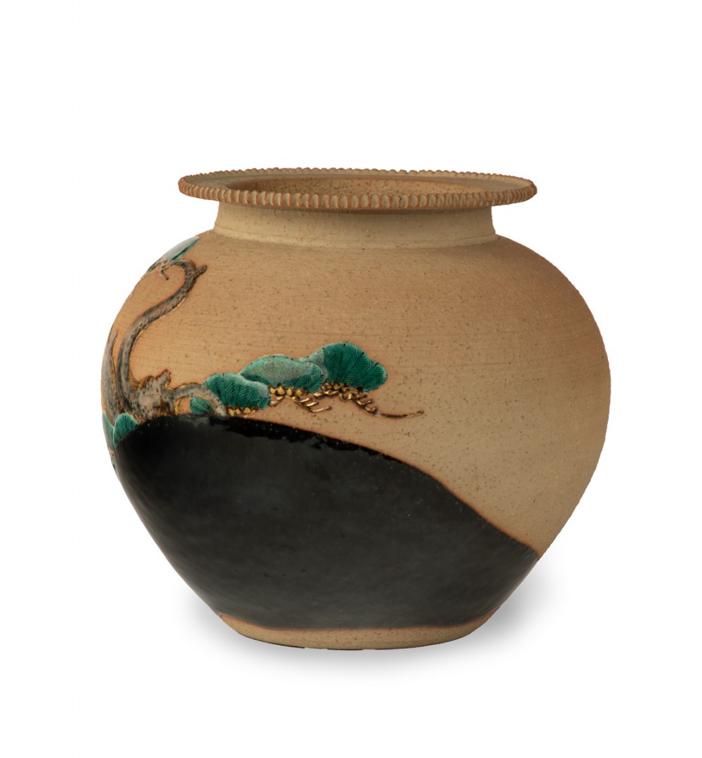 A rounded beige stoneware jardiniere decorated with high-relief green pine branches and white cranes above a black band base. View IV