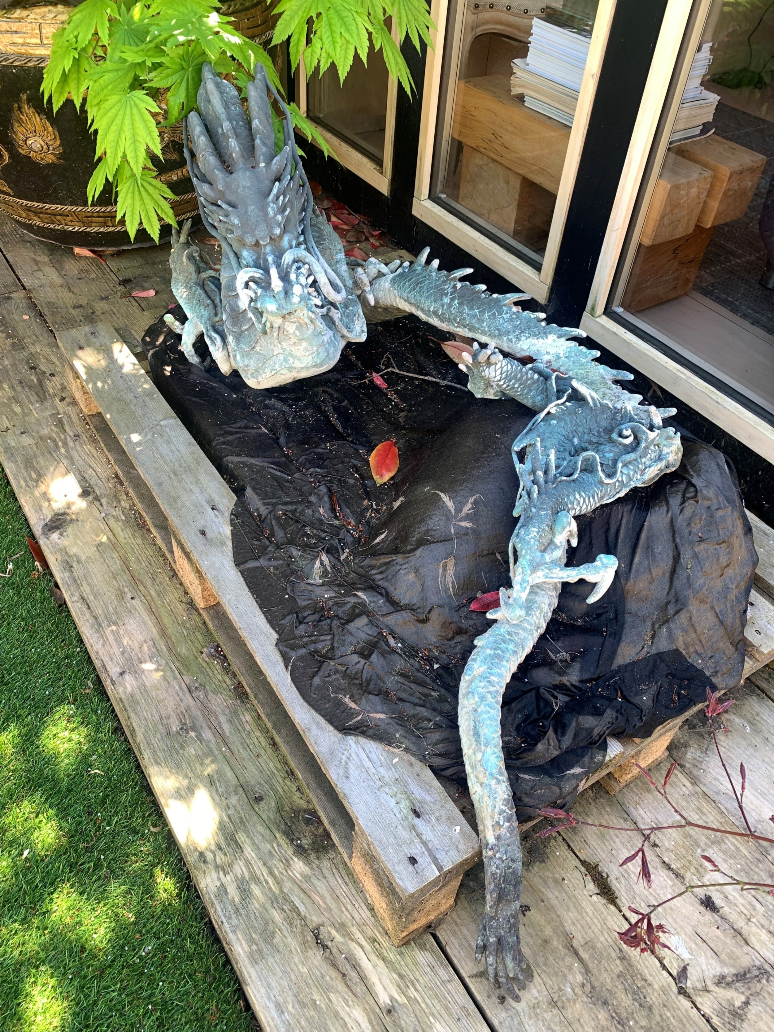 A large patinated bronze Japanese dragon sculpture with detailed chiselled scales and claws resting on a flat surface. View V