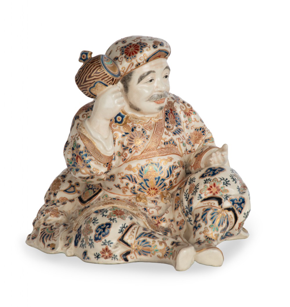 A Japanese Satsuma earthenware okimono depicting the deity Daikoku seated with a mallet and sack, decorated with detailed enamels and gilding. View II
