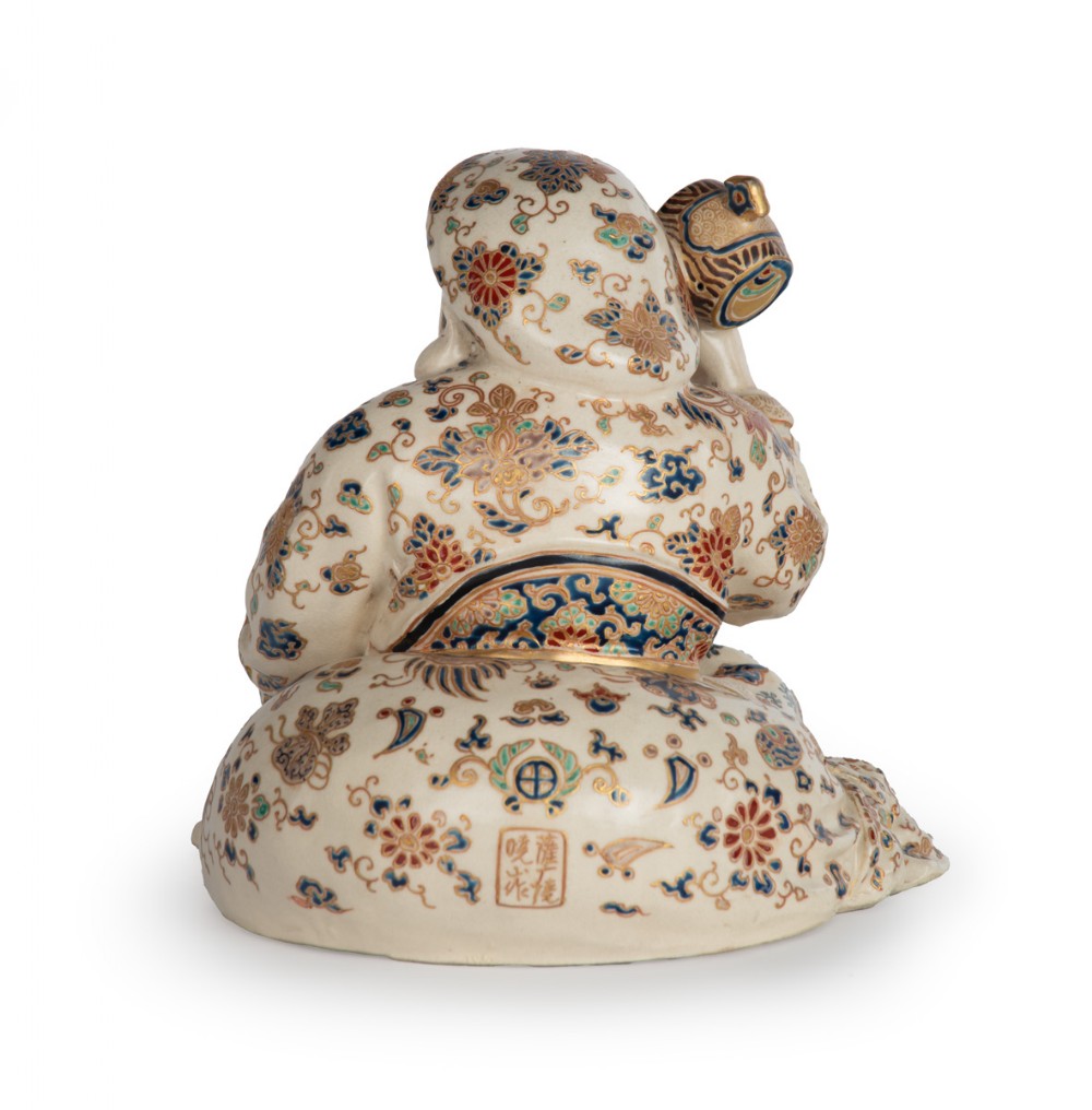 A Japanese Satsuma earthenware okimono depicting the deity Daikoku seated with a mallet and sack, decorated with detailed enamels and gilding. View V
