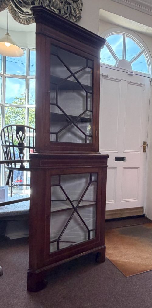 A tall two-tier mahogany corner cabinet featuring geometric glass door panes, satinwood inlay details, and bracket feet. View II